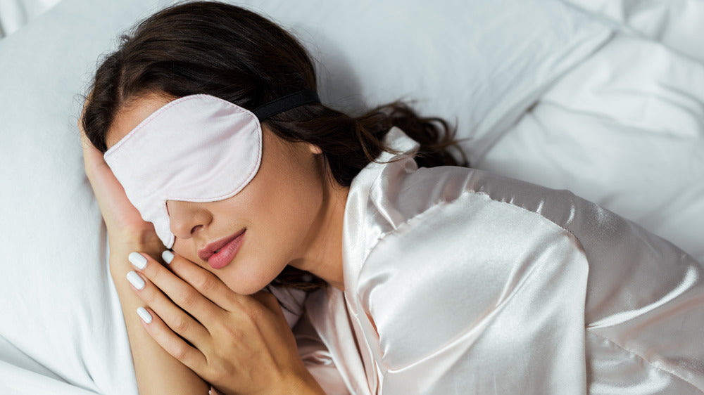 Person sleeping peacefully while wearing a silk sleep mask for improved sleep quality and nighttime comfort